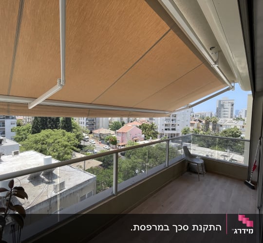 מרפסת עם סוכך חום ונוף עירוני ברקע